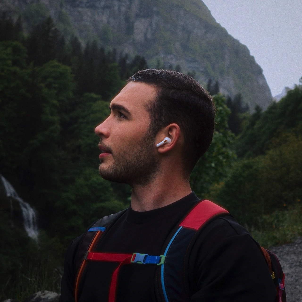 Rafael on a trail, looking toward the horizon with trees behind him